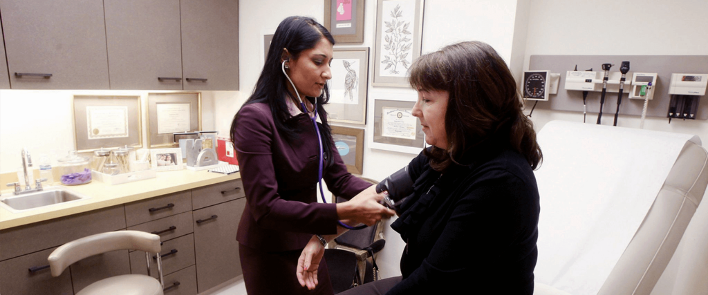 Healthcare professional checking a patient's blood pressure with a stethoscope.
