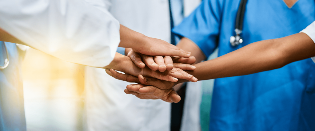 Healthcare team joining hands to symbolize collaboration and teamwork in patient care.