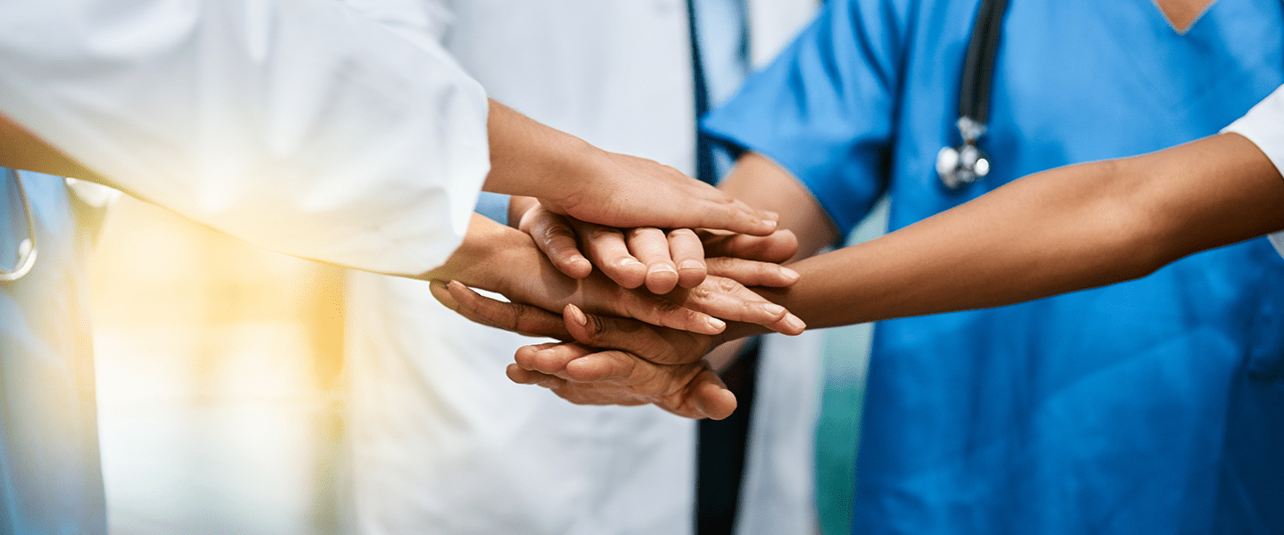 Healthcare team joining hands to symbolize collaboration and teamwork in patient care.