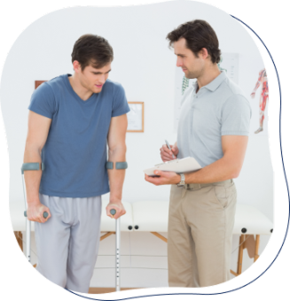A healthcare professional takes notes on a notepad while speaking with a patient who is using crutches. The patient, dressed in a blue shirt and pants, appears to be receiving medical guidance in a clinical setting.