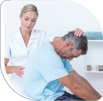 A healthcare professional helps a seated male patient with a neck or back stretch in a clinical setting.