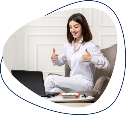 A woman in a white shirt gives two thumbs up while sitting in front of a laptop.